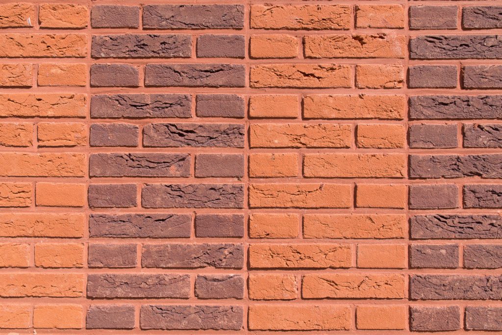 Detail van muur met verschillende kleuren baksteen in strakke rijen