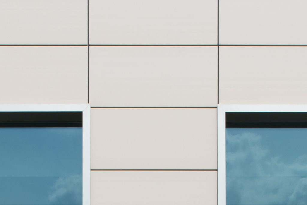 Detail van lichte tegels aan de gevel tussen twee ramen