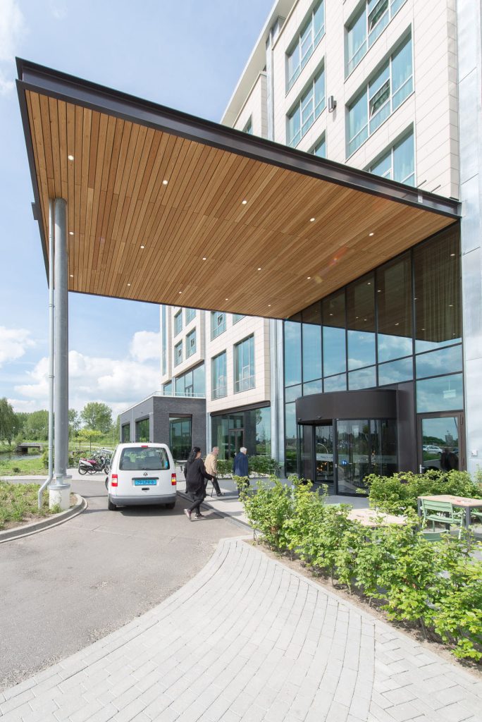 Afdak voor een gevel en een auto bij de ingang waar mensen uitstappen