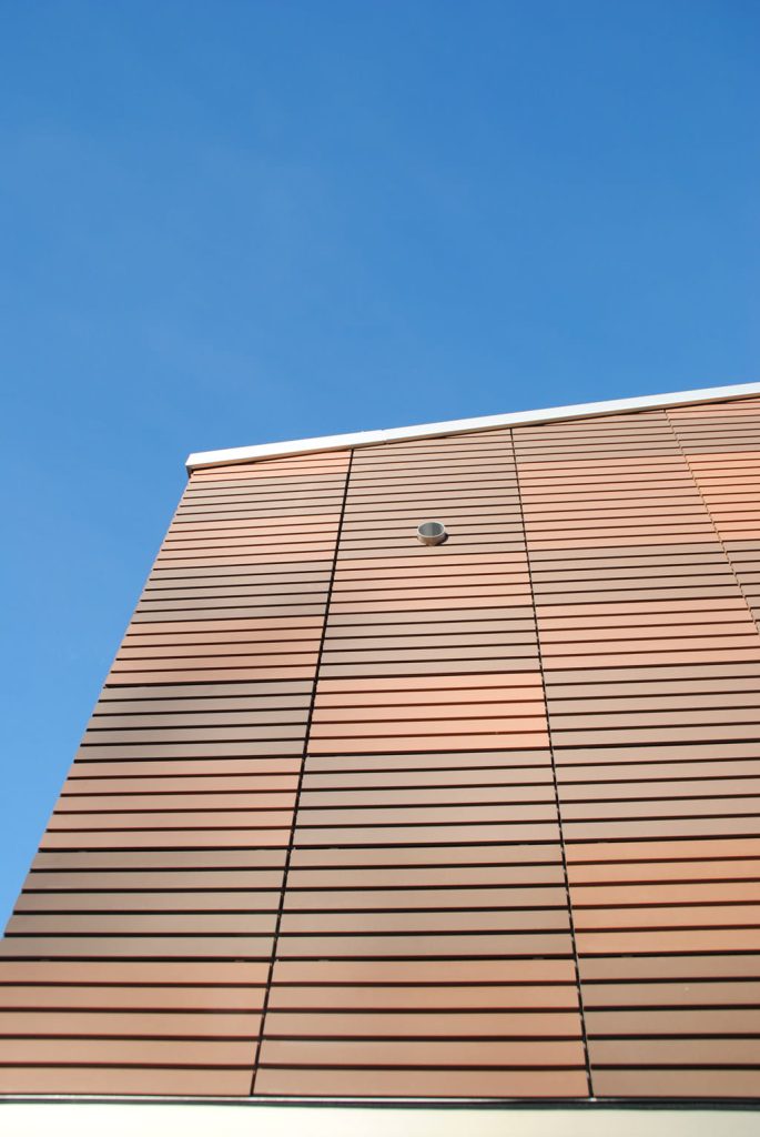 Hoek van een gevel met lichtbruine en oranjeachtig Argetontegels