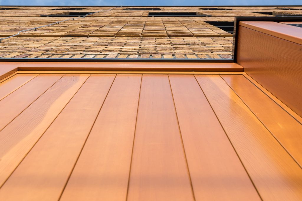 Gevel van onderen bekeken met een gedeelte oranje element en bakstenen erboven