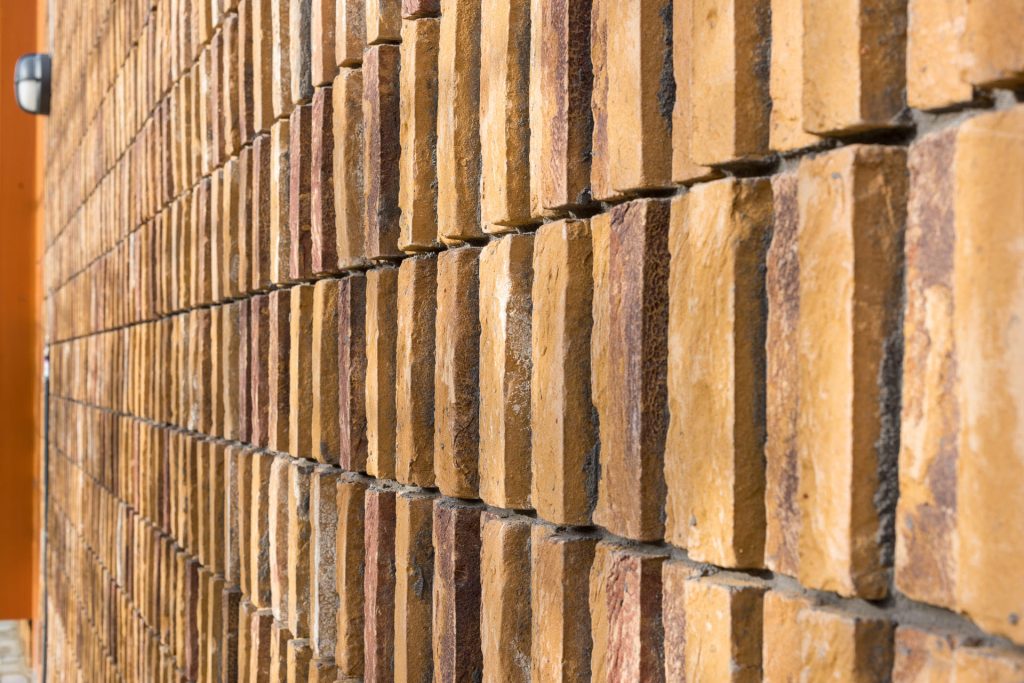 Detail van staand metselwerk met een gele steen