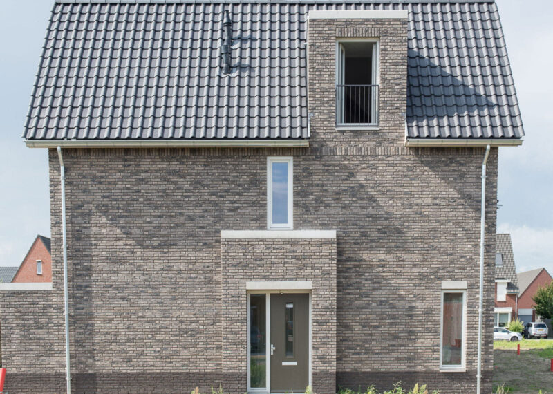 zijaanzicht van een grijsbruin huis met dakpannen