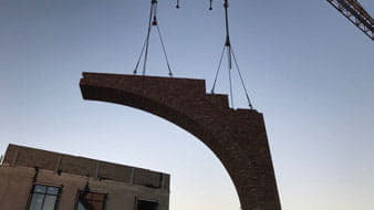 Prefab element hangt aan een hijskraan voor een gebouw