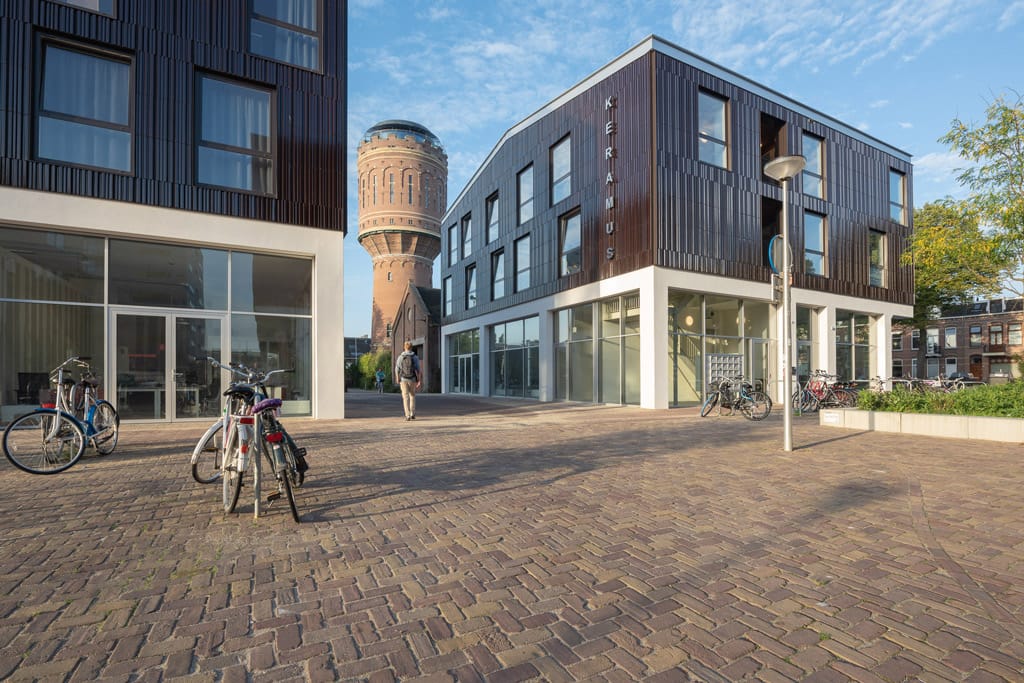 Argeton tegels bij Keramus met aan twee kanten gebouwen en een steeg ertussen met op de achtergrond een watertoren