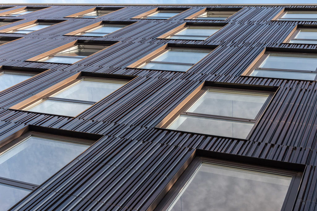 Detail van een gevel met ramen, van onderen genomen. De tegels zijn bruinig met een patroon