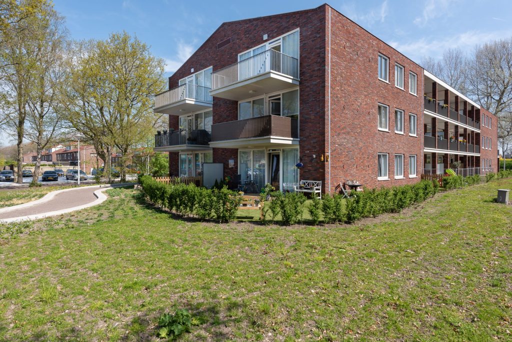 Roodbruik gebouw met balkons vanaf rechterkant bekeken tegen een blauwe lucht