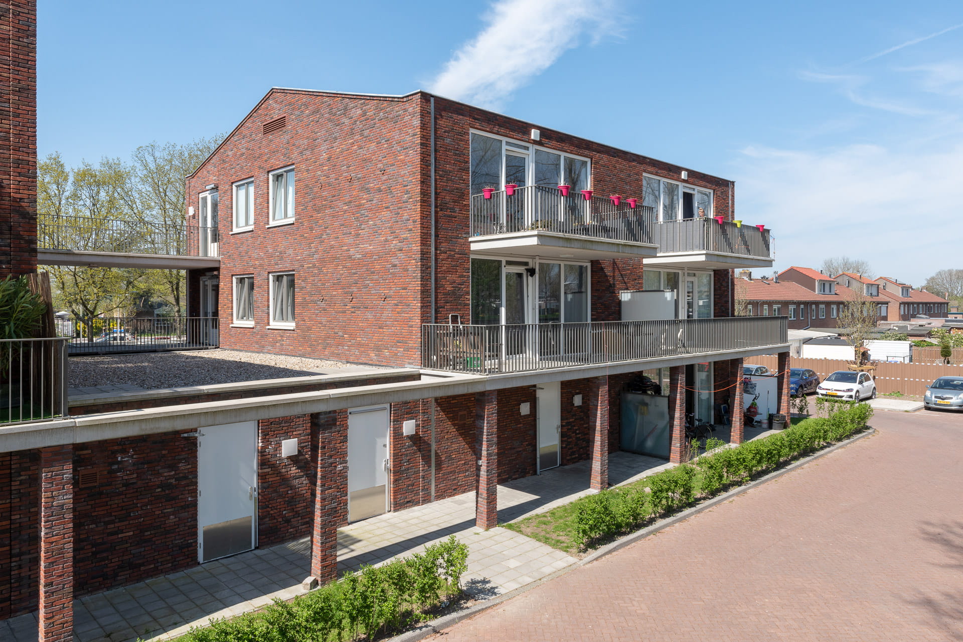 Foto van een roodbruin gebouw op dezelfde hoogte, met balkons en een overkapping