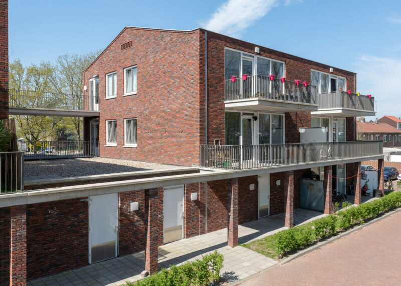 Foto van een roodbruin gebouw op dezelfde hoogte, met balkons en een overkapping