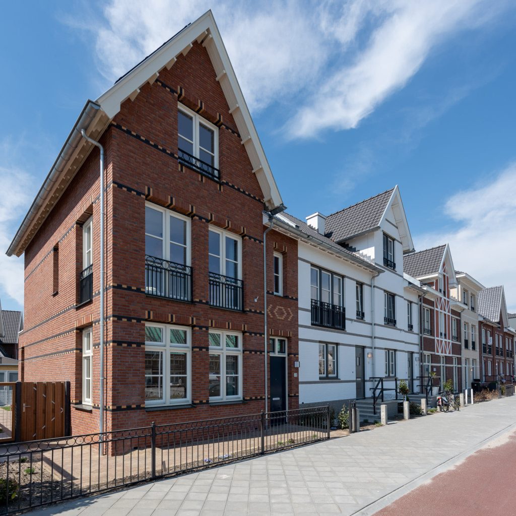 Rij nieuwbouwwoningen in negentiende-eeuwse stijl in verschillende kleuren en ontwerpen