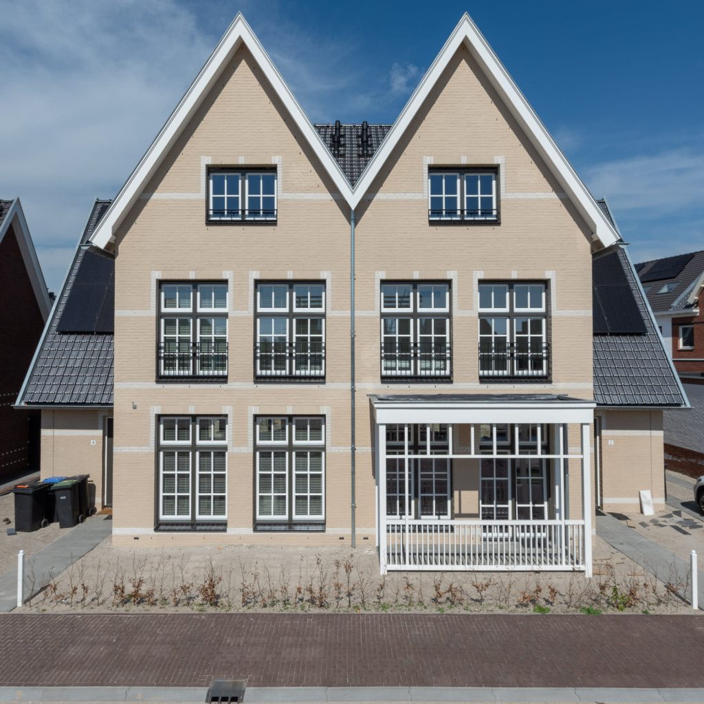 Twee-onder-een-kap woning van een lichte steen met twee puntige daken