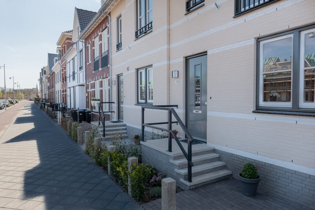 Een rij huizen vanaf de zijkant bekeken met op de voorgrond een trapje naar de voordeur