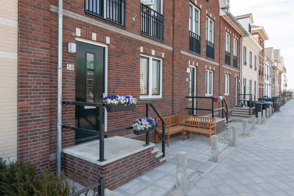 Een rij huizen vanaf de zijkant bekeken met op de voorgrond een trapje naar de voordeur