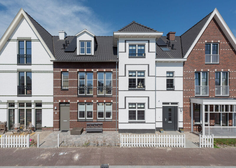 Rij van vier woningen in eind negentiende eeuwse stijl, maar nieuwgebouwd in verschillende kleuren wit en rood/bruin