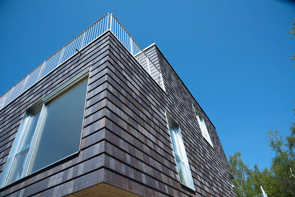 Donker gebouw van onderen gezien, met strakke lijnen van Architile tegels