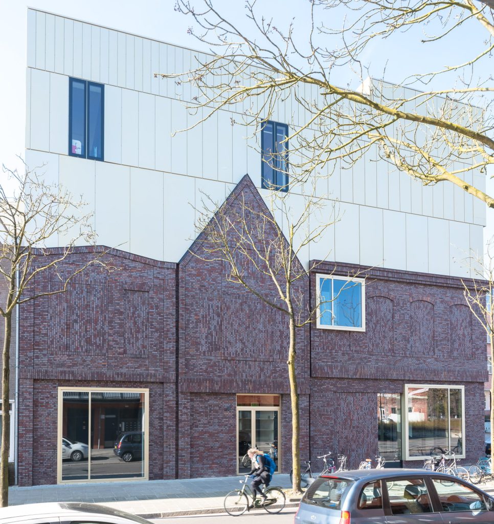 Zicht op een gevel met de onderkant stenen en de bovenkant licht materiaal