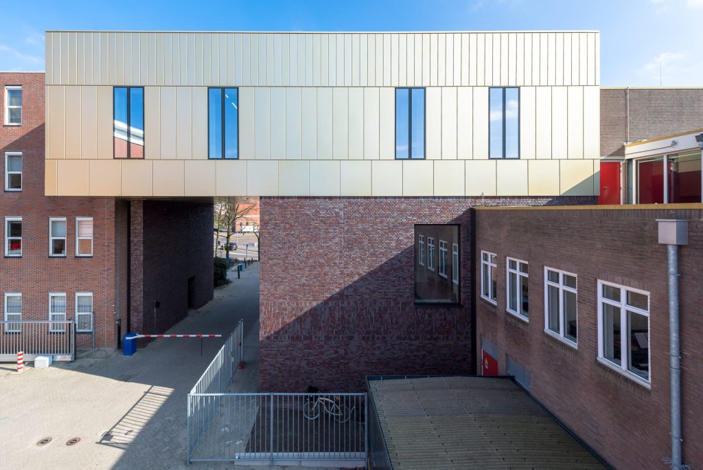 Zicht op gevel van Conservatorium Groningen met onderste laag donkere stenen en bovenste gedeelte een lichte muur.