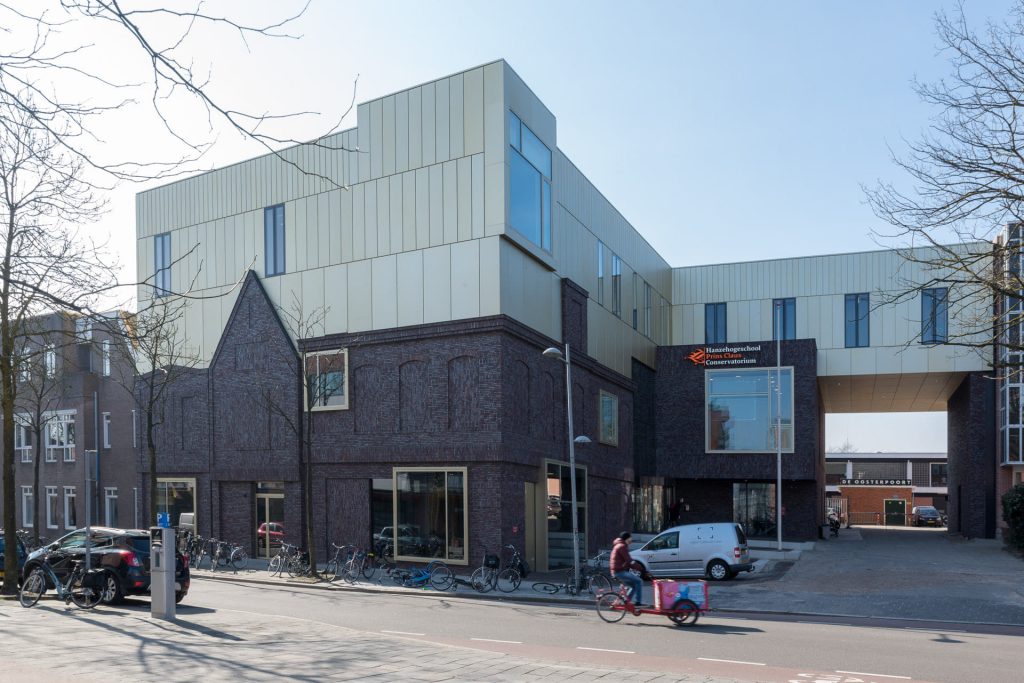 Prins Claus Conservatorium vanaf de hoek bekeken, met donkere bakstenen onder en lichte gevel boven.