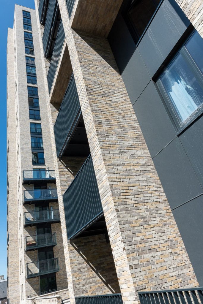 Zijkant van een toren met hoge muren met lichte bakstenen en steenstrips en schaduwen