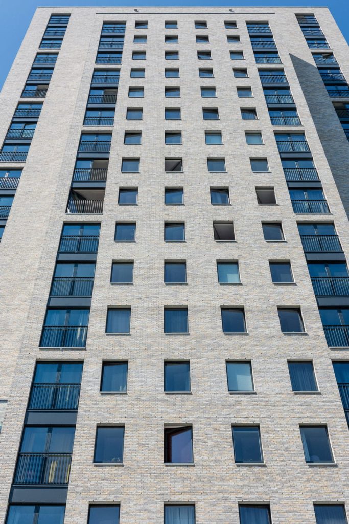 Een toren met lichte gevelstenen en ramen van onderen naar boven bekeken