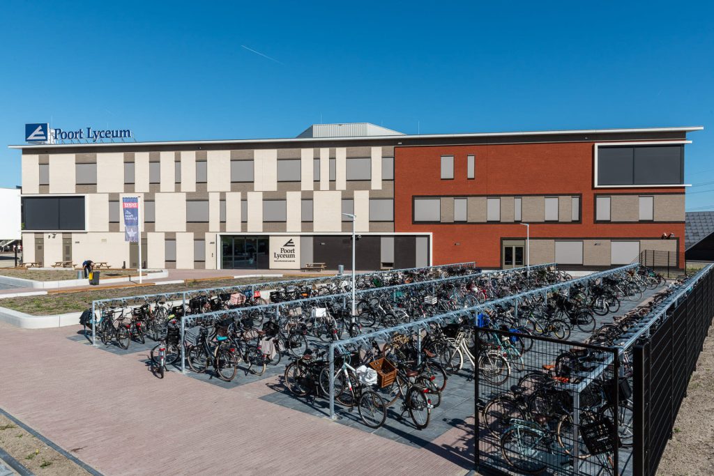 Gevel van het Poort Lyceum in Almere met aan de linkerkant witte vlakken en rechterkant rode vlakken