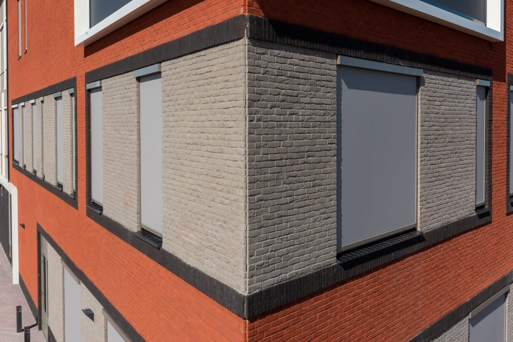 Hoek van een gebouw met rode en lichte vlakken
