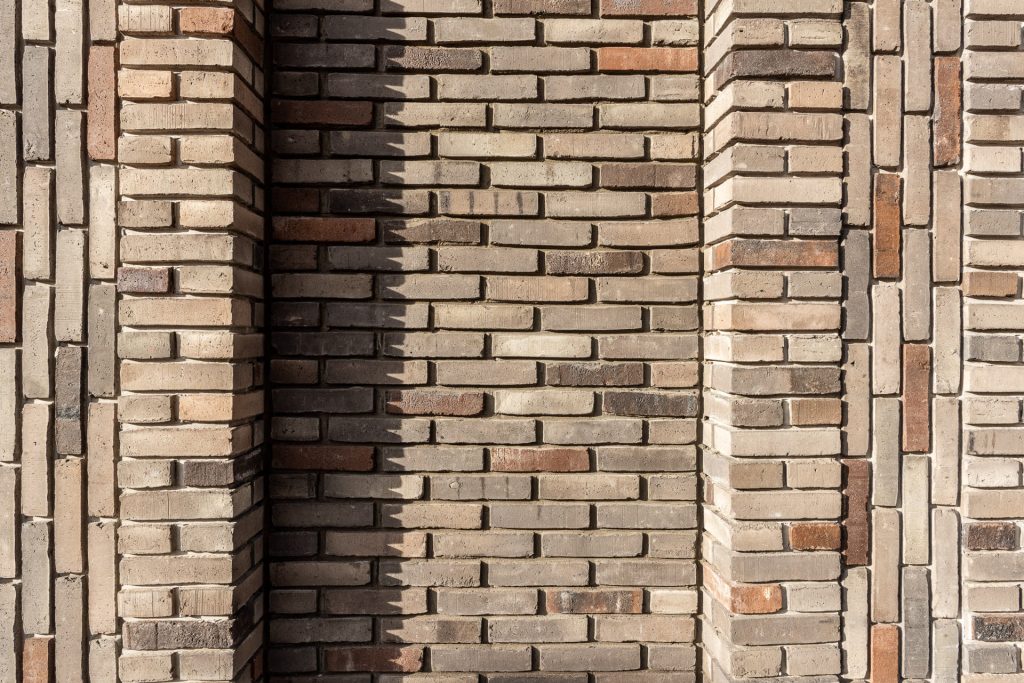 detail van een lichte gevel met uitstekend en terugliggend metselwerk