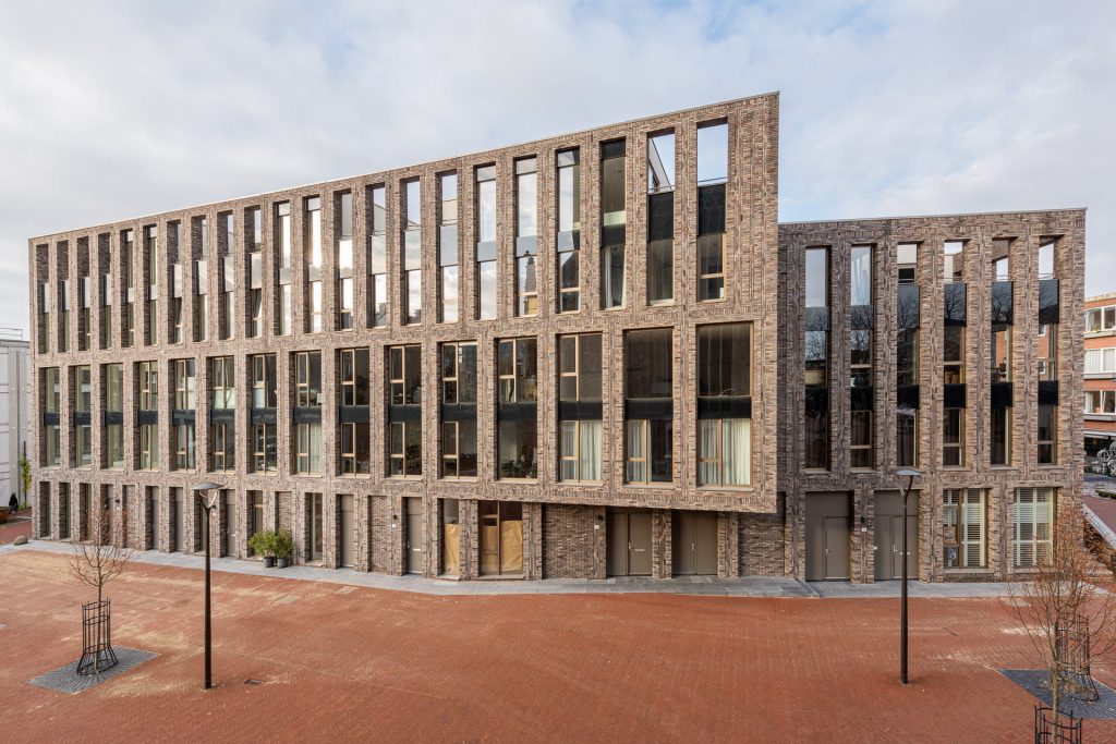 zijaanzicht van een grote partij ramen en lijnen in de gevel met op de voorgrond een plein