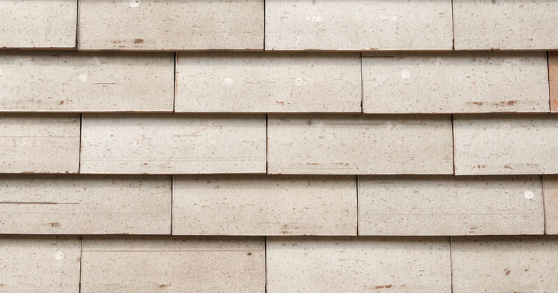 Detail van een lichte muur met grote sidings van het gevelsysteem Pantheon Nordic die gepotdekseld zijn gemonteerd