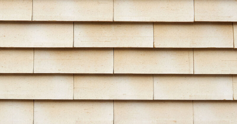 Detail van een lichte muur met grote sidings van het gevelsysteem Pantheon Nordic die gepotdekseld zijn gemonteerd