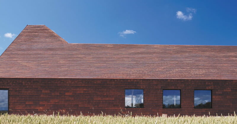 Langwerpig gebouw in een graanveld, geheel in het keramische gevelsysteem Pantheon Nordic