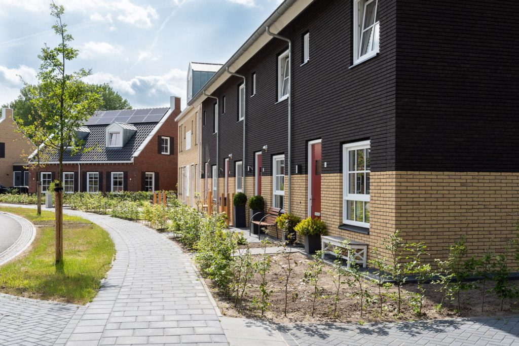 Een rij huizen met een gevel waarvan de bovenste helft donkere bakstenen heeft en onder lichte gevelstenen