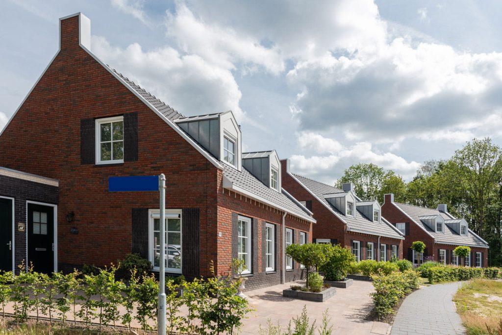 Rij met huizen met roodbruine bakstenen en donkere dakpannen