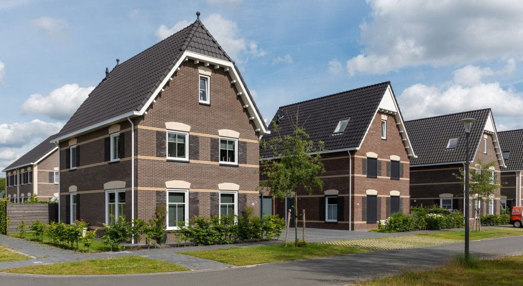 Twee vrijstaande huizen met donkere gevelstenen en zwarte dakpannen