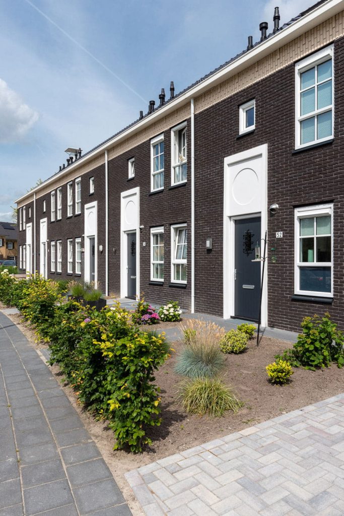 Rijwoning met donkere steen en witte vlakken en groen ervoor