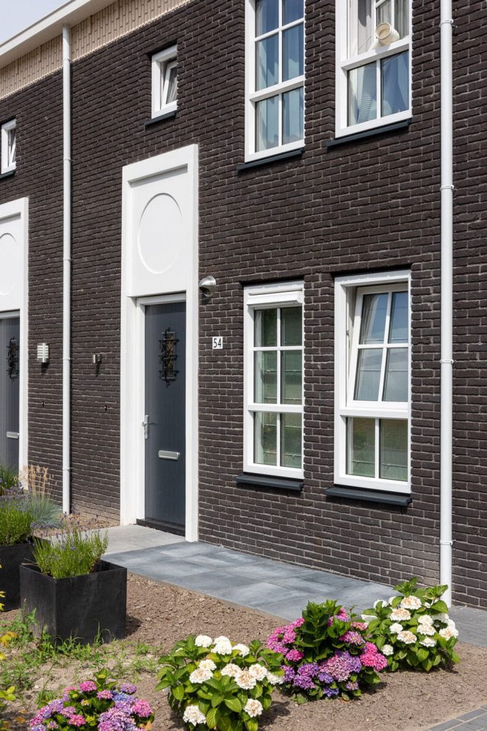 Rijwoning met donkere gevelsteen en tuin ervoor