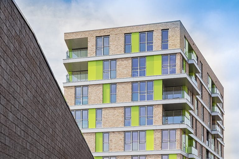 Gevel met ClickBrick, ramen en groene elementen tegen een blauwe luchtGevel met ClickBrick, ramen en groene elementen tegen een blauwe lucht