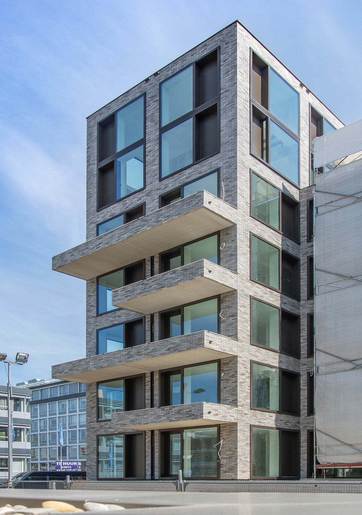 Hoogbouw met balkons en een grijze steenstrip op het systeem van Sto