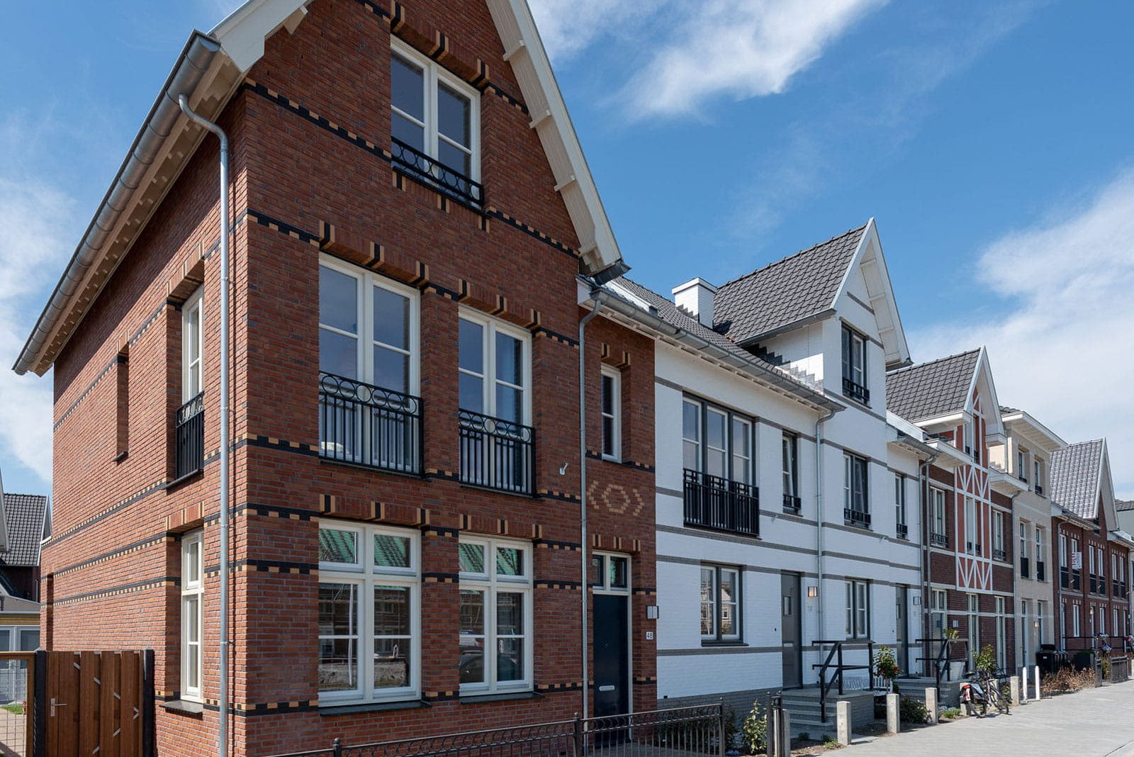 Zicht op een rij roodbruine en witte woningen met een puntdak